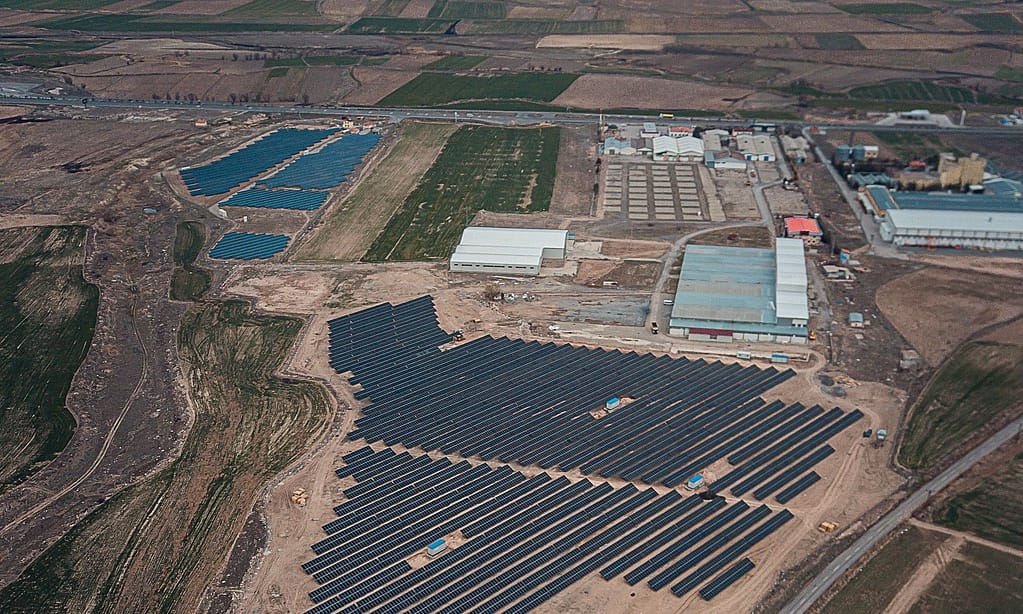 Vista aérea de una planta fotovoltaica en suelo junto a un polígono industrial