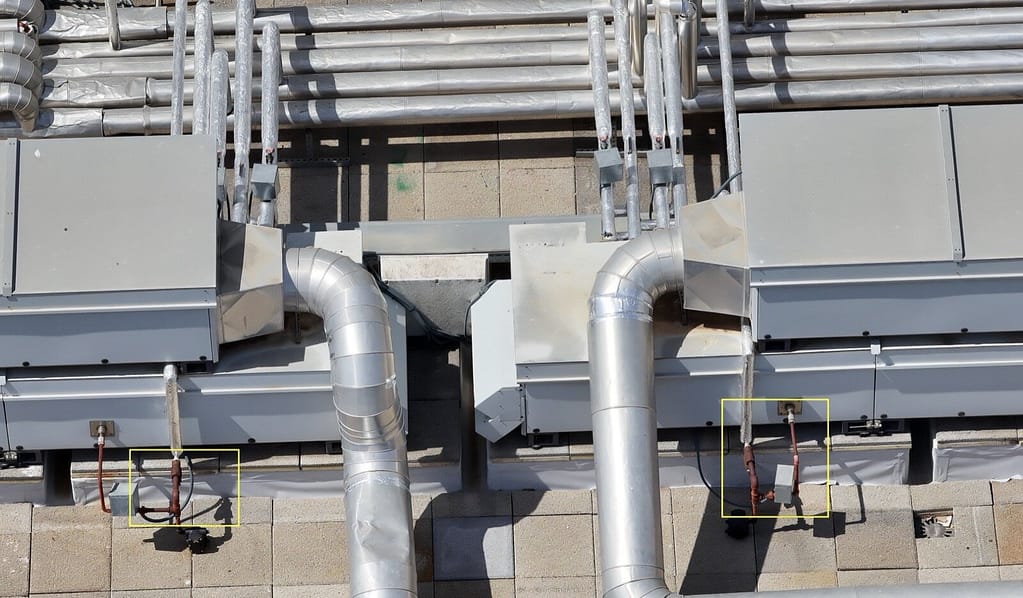 Imagen aérea cercana de cubierta industrial mostrando conductos HVAC con anomalías marcadas en cajas amarillas