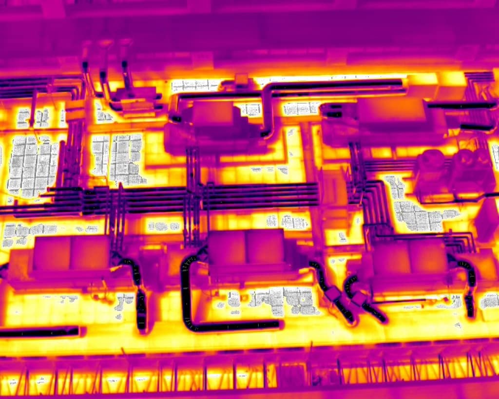 Termografia aerea de cubierta industrial mostrando equipos HVAC, conductos y zonas térmicas anómalas en colores violeta y amarillo