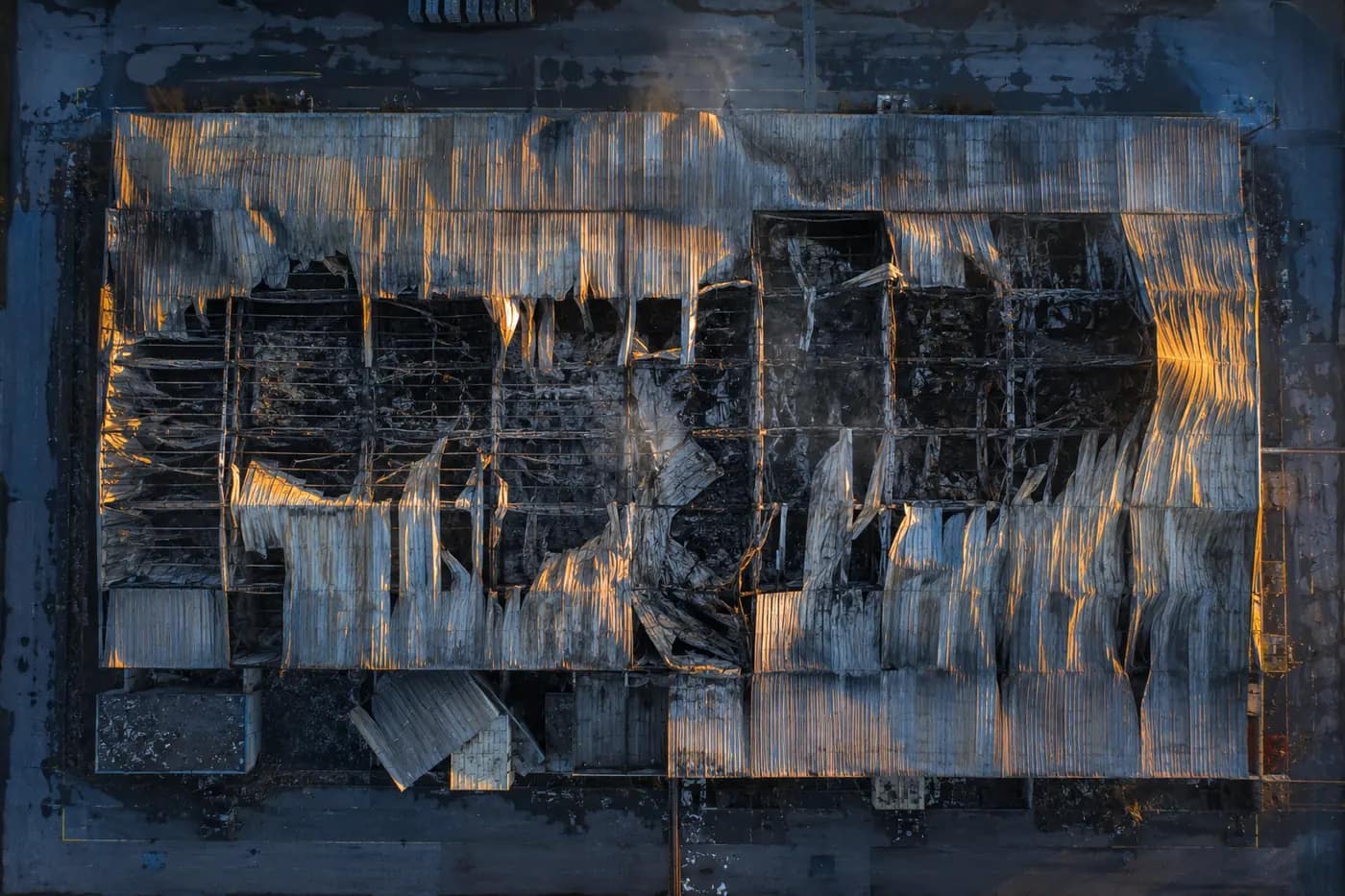 Vista aérea cenital de una nave industrial quemada con la cubierta colapsada tras un incendio, documentada con dron para la evaluación de daños