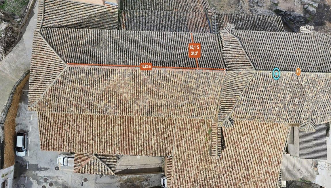Vista aérea de las cubiertas de un conjunto de edificios inspeccionadas con dron, con mediciones de pendiente y longitud